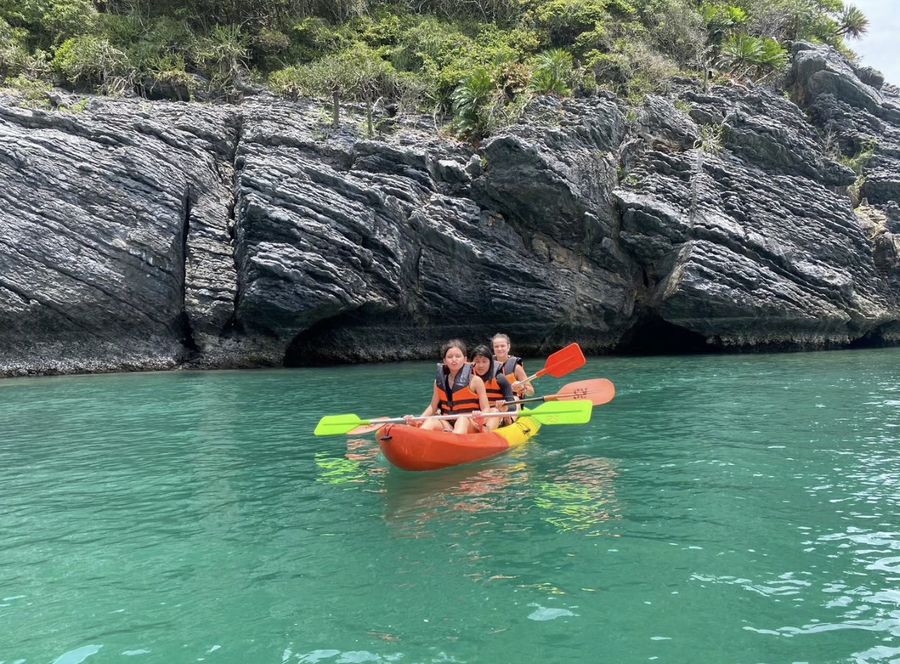 Guests kayaking beside limestone cliffs