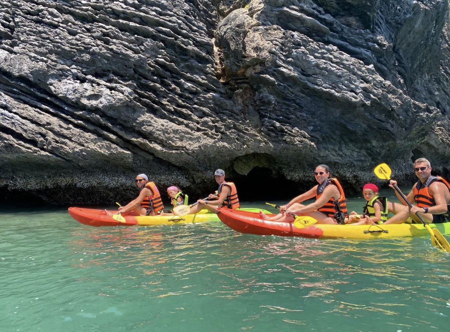 Families in kayaks under the cliffs