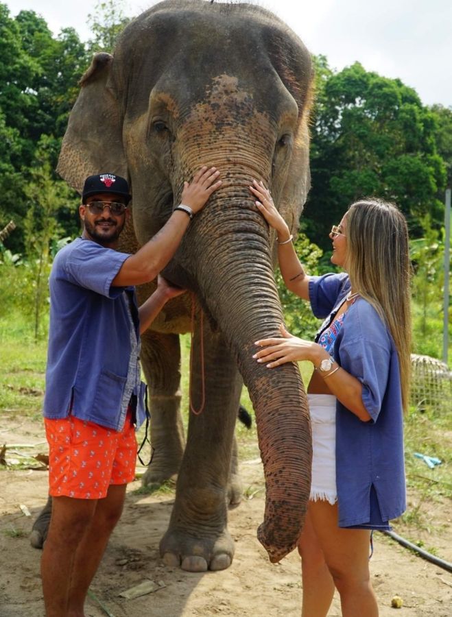 Two guests standing with an elephant