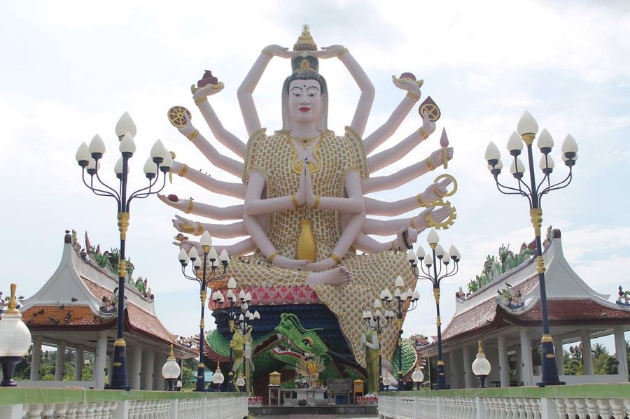 Temple statue with many arms, flanked by lamp posts