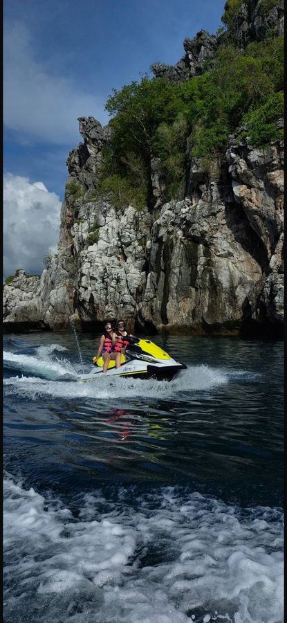 Two guests riding a jet ski past limestone cliffs