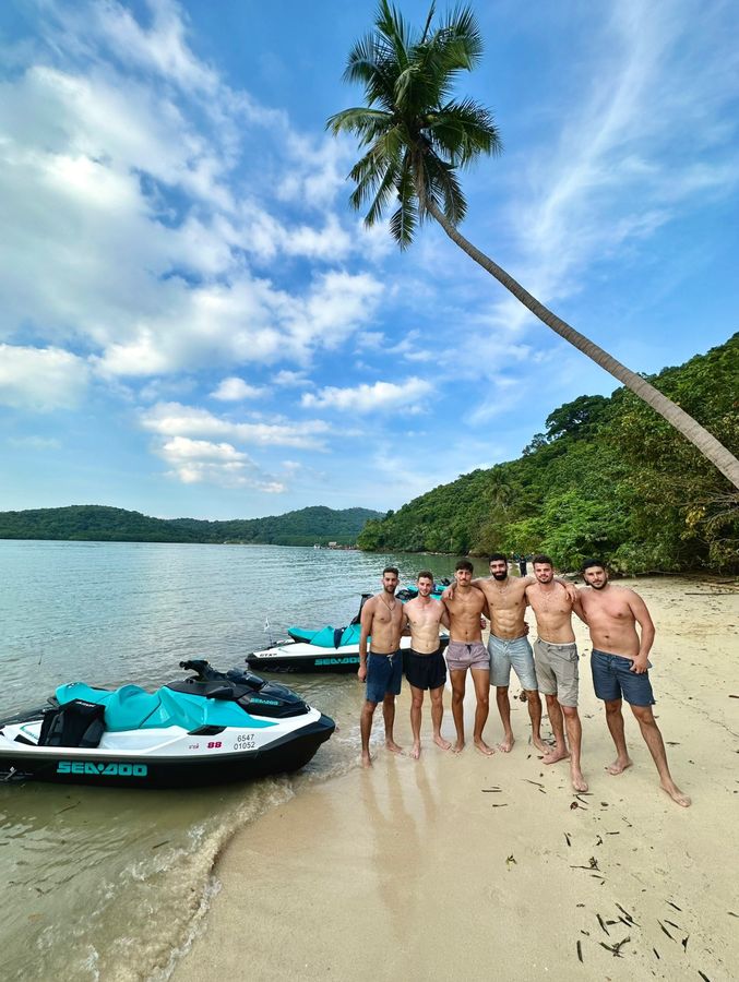 Group of guests on a beach beside their jet skis