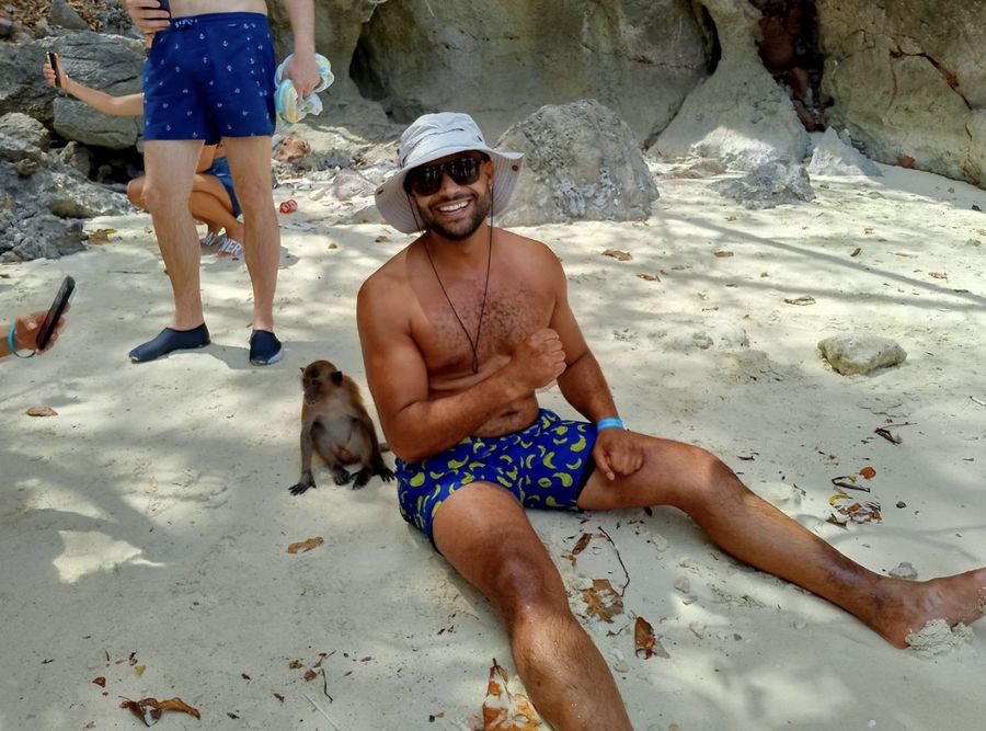 Guest sitting on the sand next to a monkey